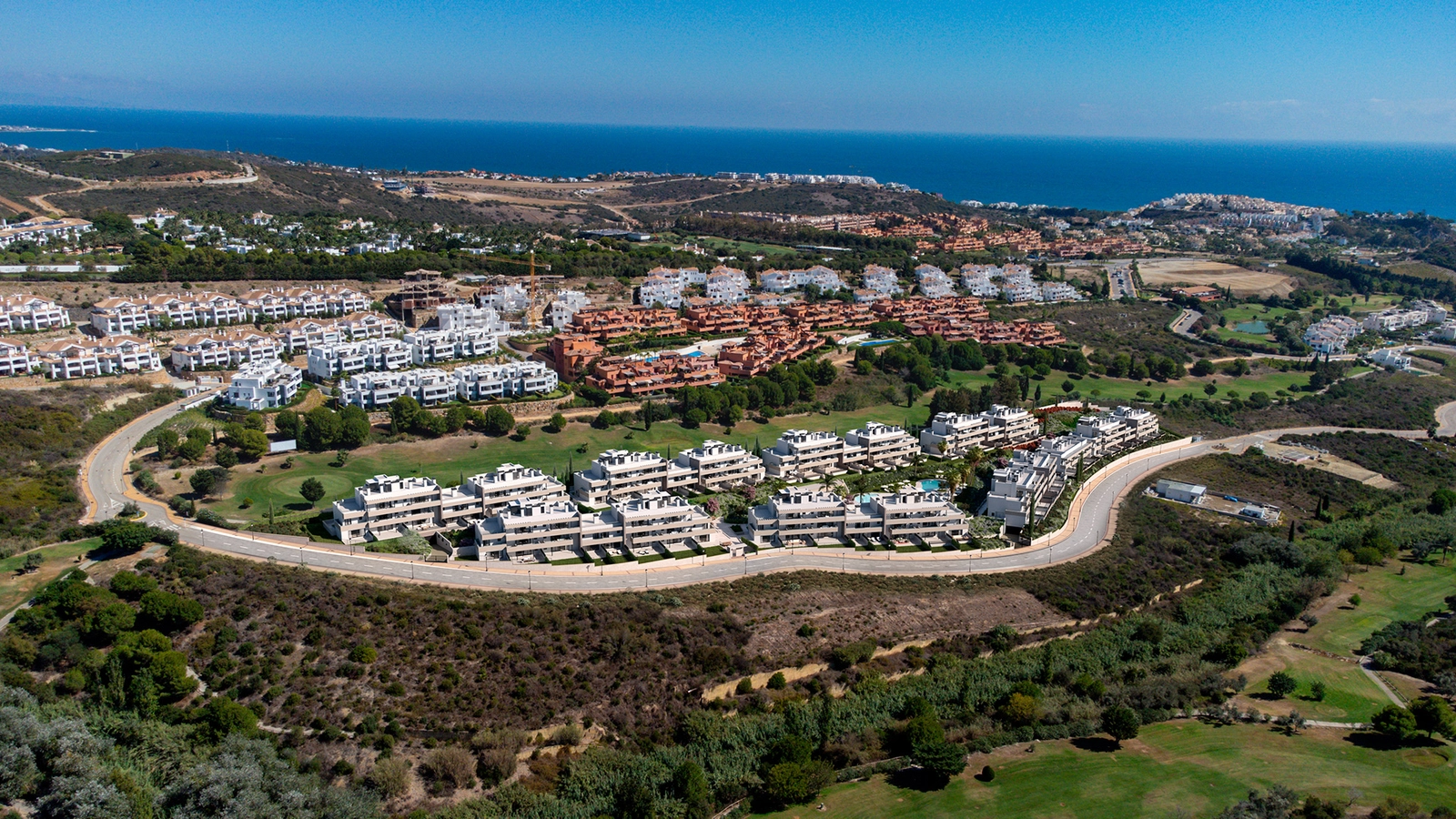 En flygvy över bostadsområdet, perfekt integrerat i Casares golfbanas gröna landskap, med Medelhavet bortom.