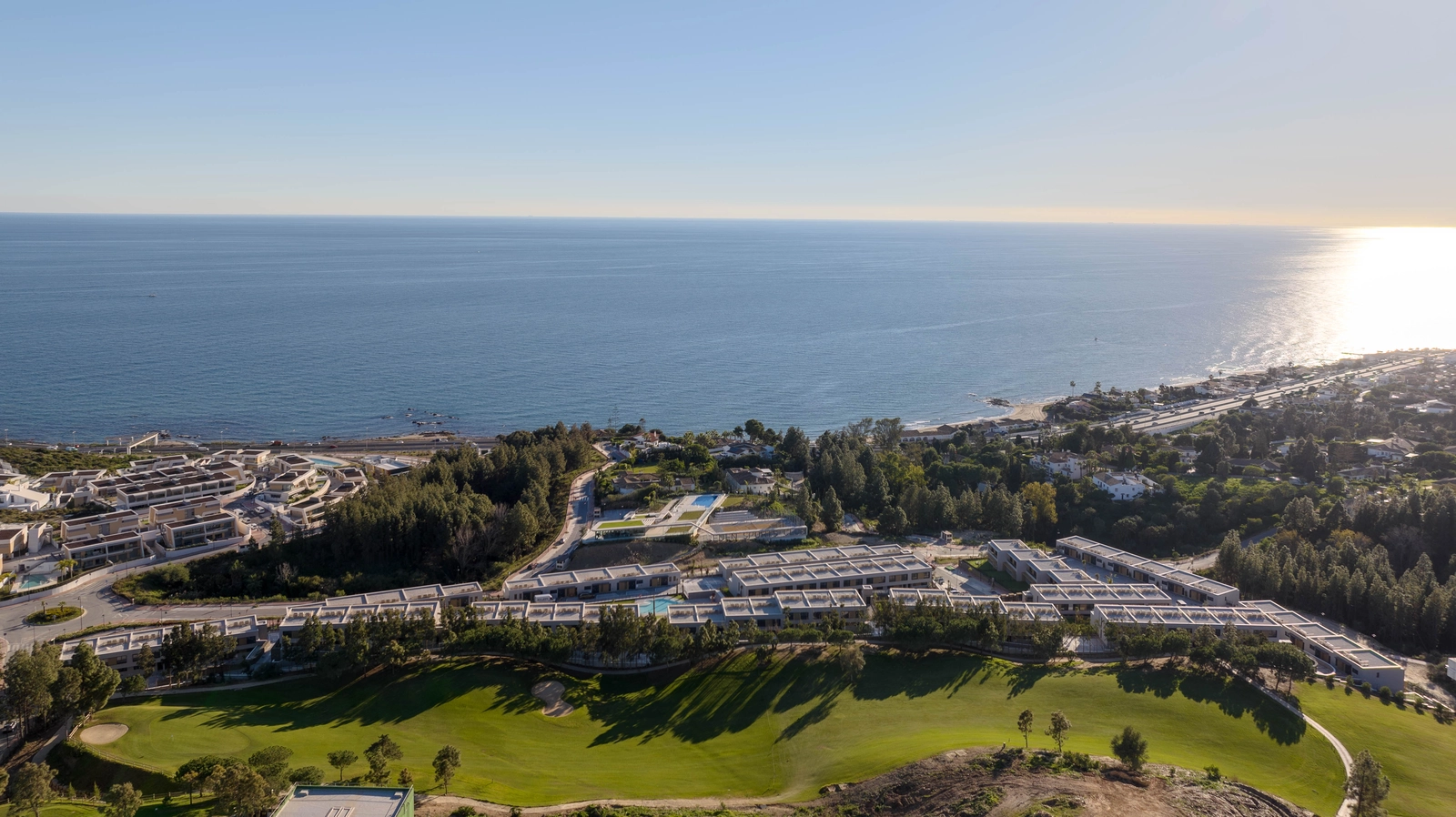 En flygvy över Evergreen Homes, perfekt beläget mellan golfbanans gröna fairways och det blå Medelhavet.