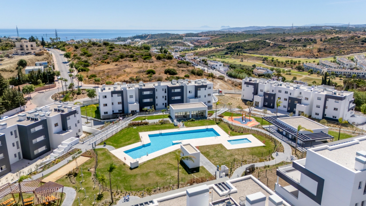 Ett underbart perspektiv av det färdigställda bostadsområdet, som visar poolerna och grönområdena med havet vid horisonten.
