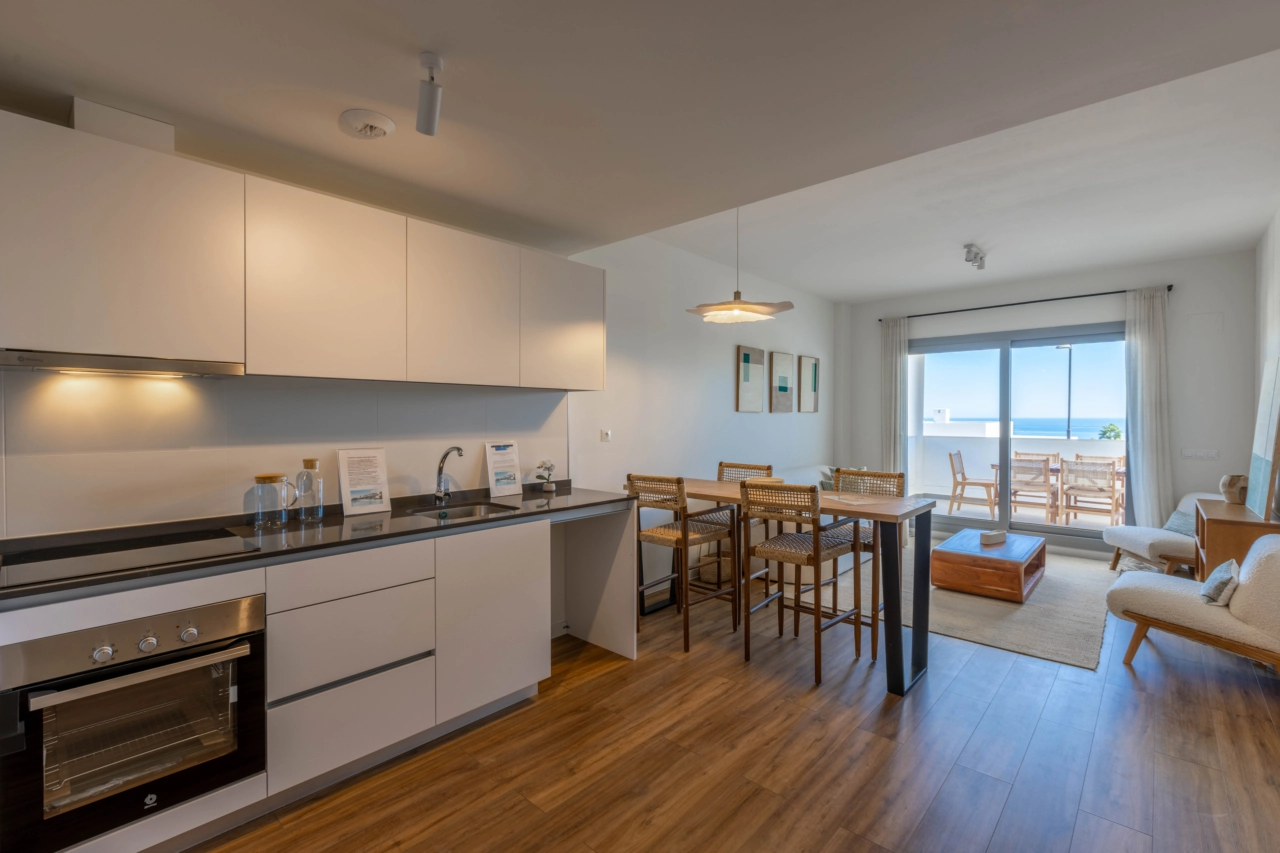 Ett modernt, fullt utrustat kök öppnar upp mot vardagsrummet och skapar en ljus och social mittpunkt i hemmet.