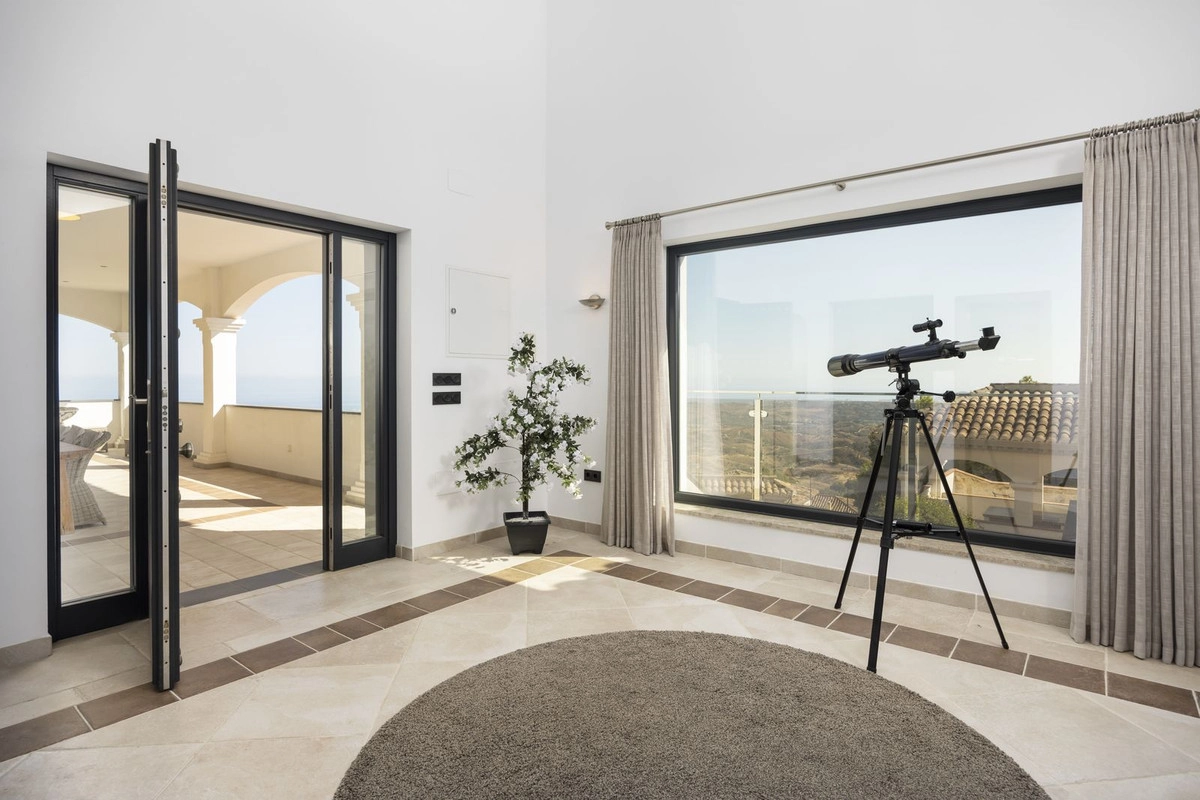 Ett lugnt hörn av hemmet där stora fönster ramar in det spektakulära landskapet och dörrar öppnar upp mot terrassen.