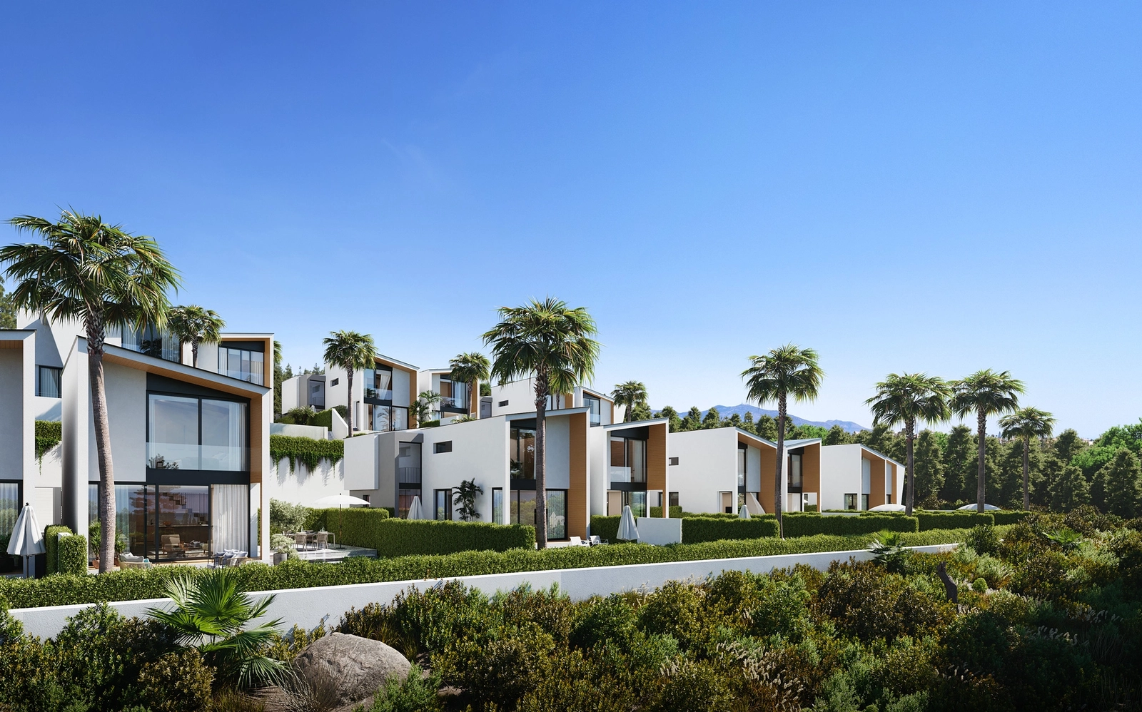 Villornas slående moderna arkitektur sticker ut mot den klarblå himlen och de lummiga gröna omgivningarna.